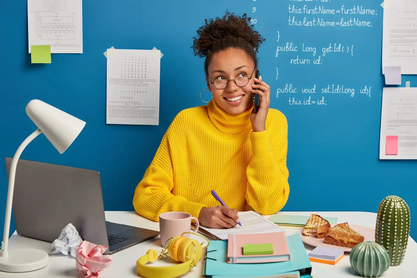 Une apprenante révise son anglais au téléphone, souriante, à son bureau